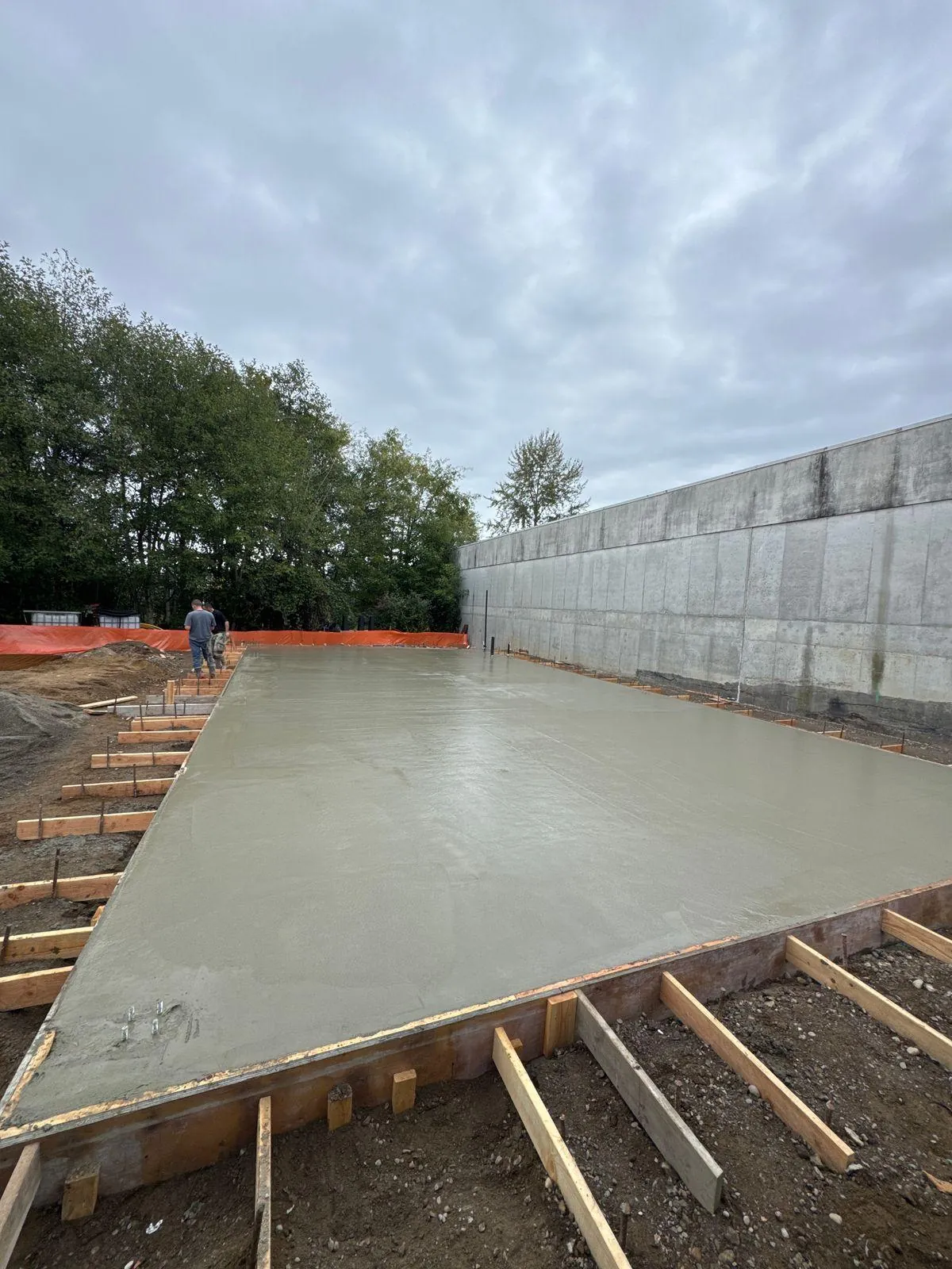 The newly placed concrete slab taking shape within the foundation forms.